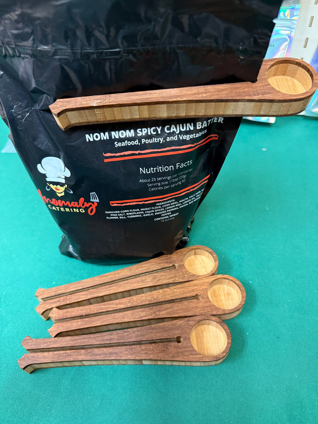 Wooden coffee scoop clipping a bag closed, shown with the scoops beside it