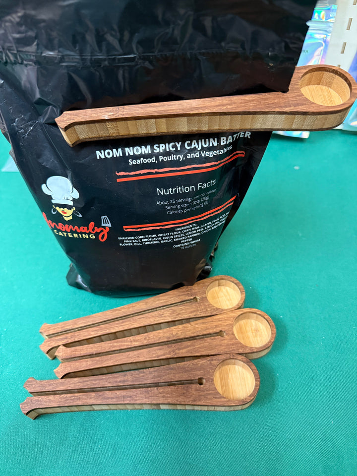 Wooden coffee scoop clipping a bag closed, shown with the scoops beside it