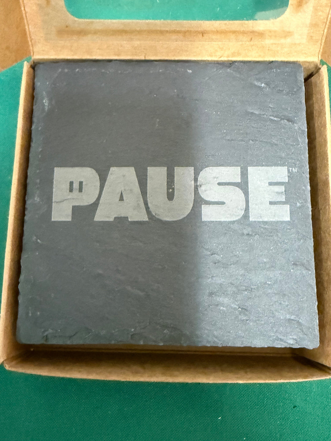 Slate PAUSE coaster engraved with the PAUSE mark, sitting in its kraft gift box